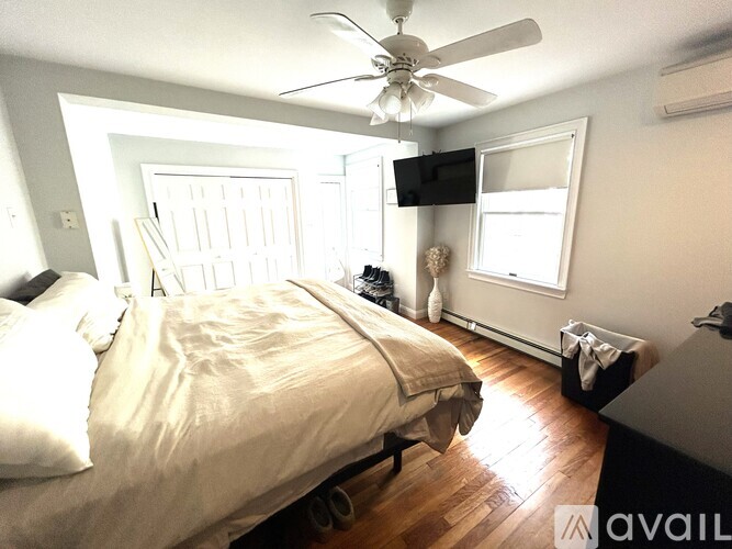 A bedroom with a bed, a ceiling fan, and a window.