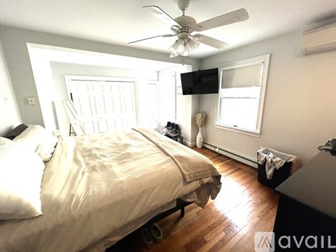 A bedroom with a bed, a ceiling fan, and a window.