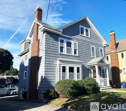 A two-story house with a grey exterior and a brick chimney.