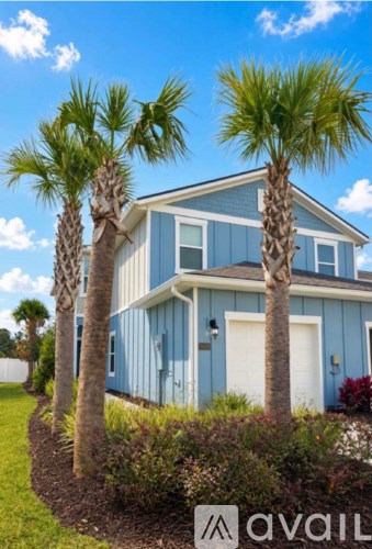 A blue house with two palm trees in front.