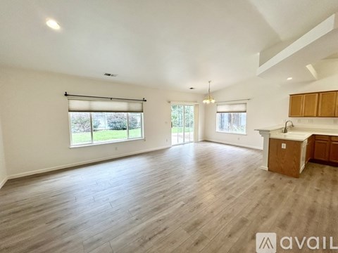 A spacious room with wooden flooring and a kitchen area with wooden cabinets.