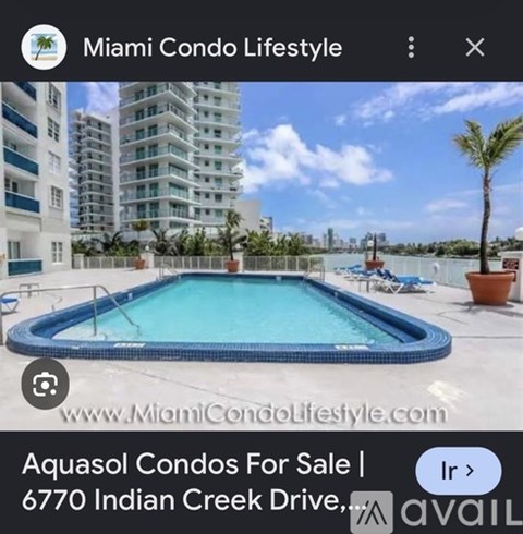A pool in front of a building with a sign that says "Aquasol Condos For Sale".