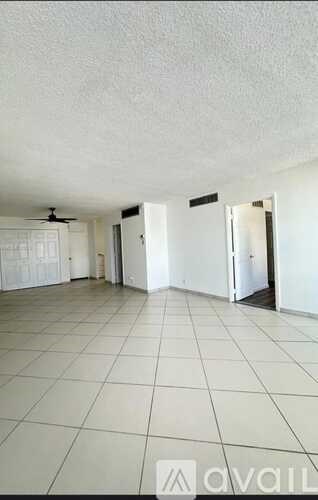 A spacious room with white tiled flooring and white walls.
