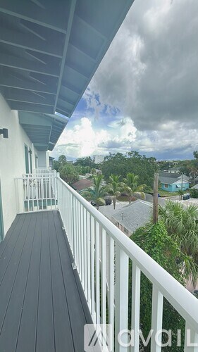 A balcony with a white railing and a view of the sky and trees.