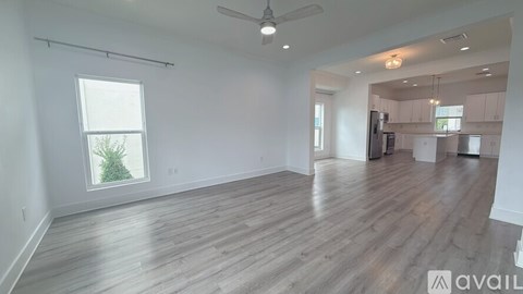 A spacious room with wooden flooring and a ceiling fan.