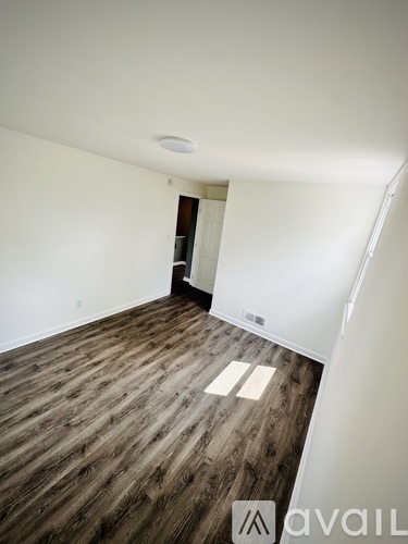 A room with wooden flooring and a door on the left side.