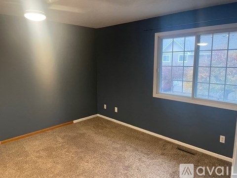 A room with a carpeted floor and a window showing a view of a building outside.