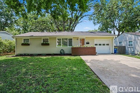 A house with a garage and a driveway is surrounded by trees.