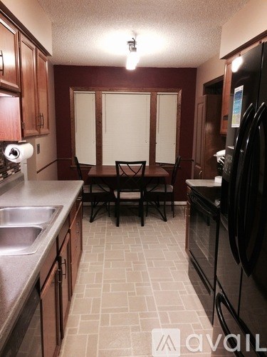 A kitchen with a black refrigerator and brown cabinets.