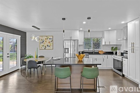A kitchen with white cabinets and a dining table with chairs.