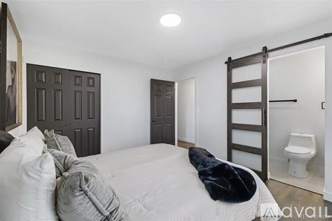 A bedroom with a white bed and a black fur throw.