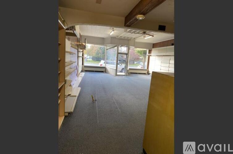 A room with a carpeted floor and a window with blinds.