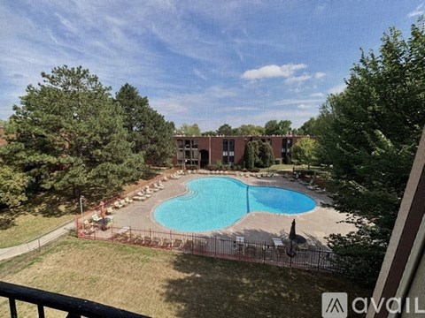 A pool surrounded by trees and a building in the background.