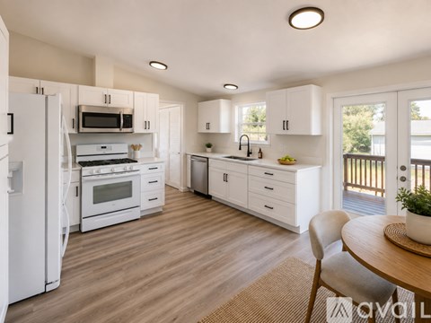 A modern kitchen with white appliances and wooden floors.