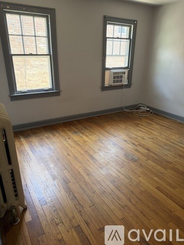 A room with wooden floors and two windows.