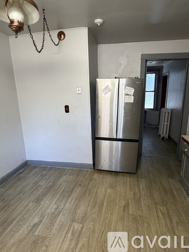A kitchen with a stainless steel refrigerator and wooden flooring.
