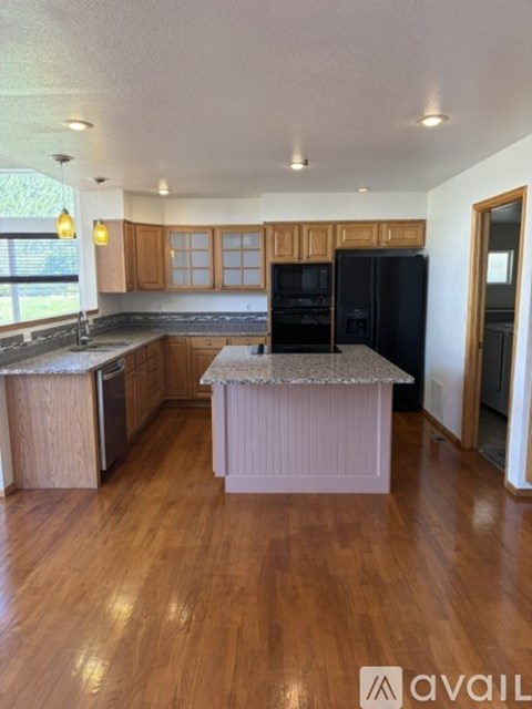 A kitchen with wooden cabinets and a black refrigerator.