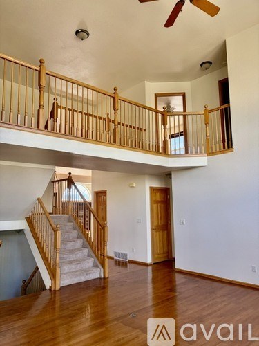 A living room with a staircase and a ceiling fan.
