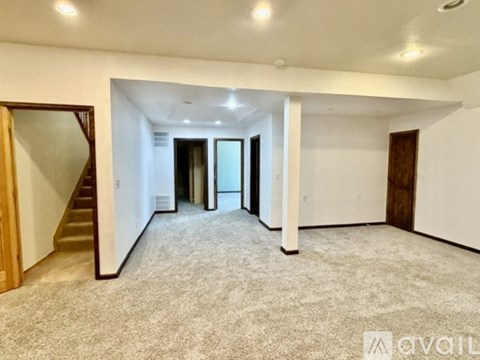 A spacious room with a staircase and a carpeted floor.