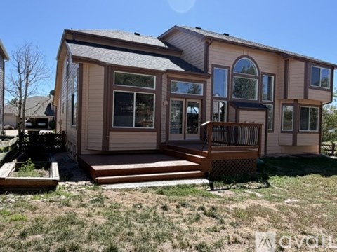 A house with a brown and beige exterior and a deck in front.