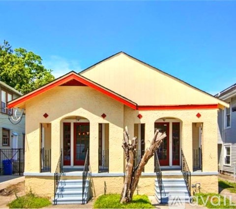 A yellow house with red trim and a red door.
