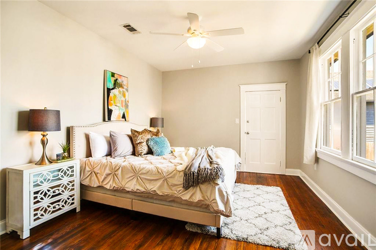 A bedroom with a bed, nightstand, and a painting on the wall.