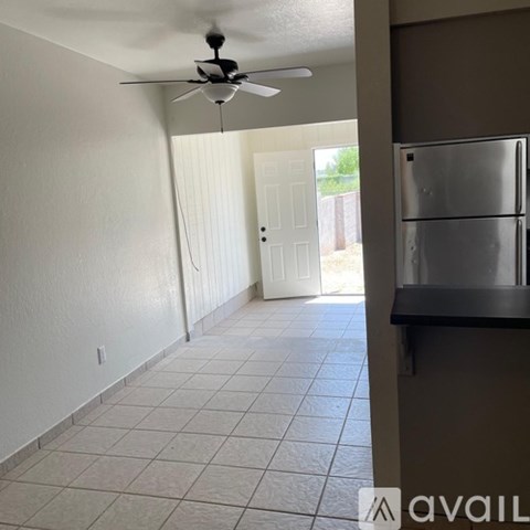 A kitchen with a refrigerator and a ceiling fan.