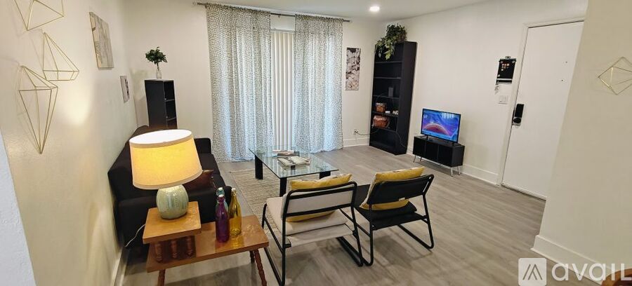 A living room with a sofa, a chair, a table with a lamp, a TV, and a bookshelf.