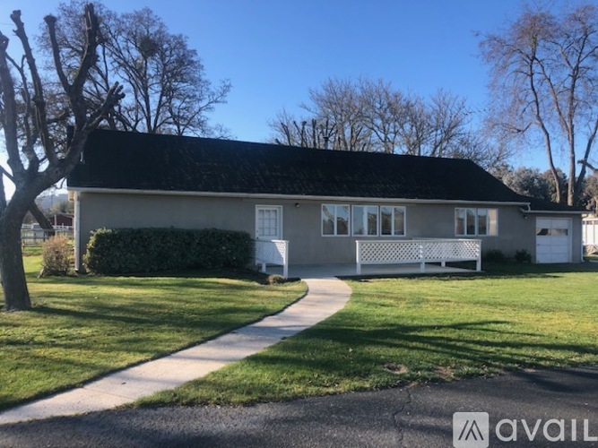 A house with a white fence and a black roof is available for sale.