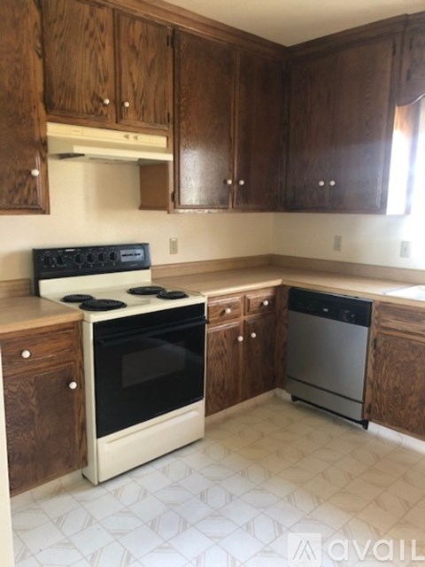 A kitchen with wooden cabinets and a white stove top oven.