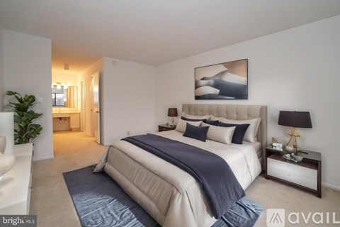 A bedroom with a large bed and a painting on the wall.