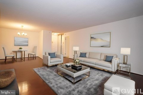 A living room with a white sofa, a grey rug, and a wooden coffee table.