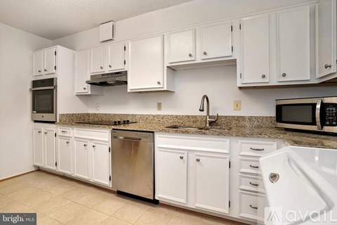 A kitchen with white cabinets and appliances.