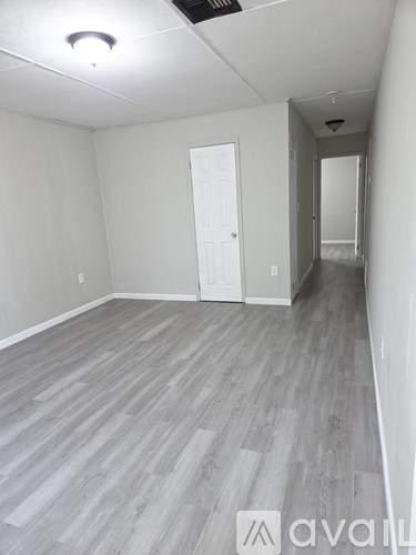 A room with a white door and a grey floor.