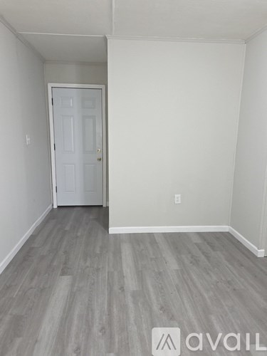 A room with a white door and grey flooring.
