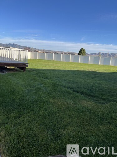 A grassy field with a mountain in the distance and a fence in the foreground.