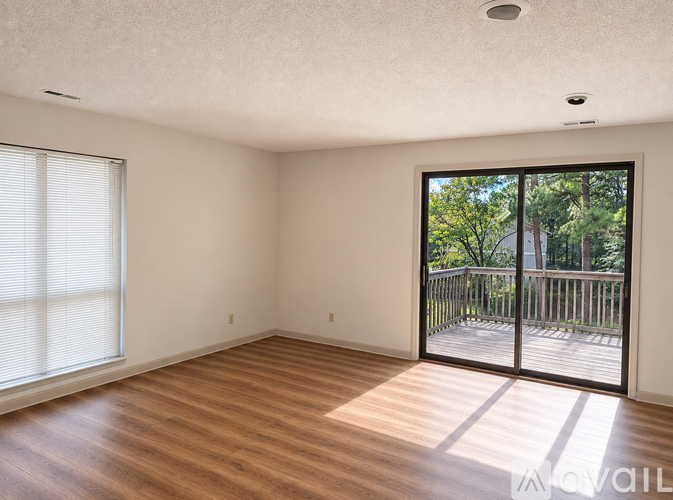 A room with wooden floors and a sliding glass door leading to a deck.