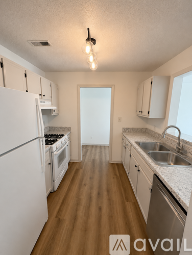 A kitchen with white appliances and wooden floors.