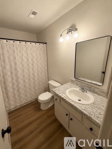 A bathroom with a toilet, sink, and shower.