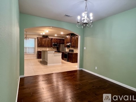 A spacious room with wood flooring and a chandelier.