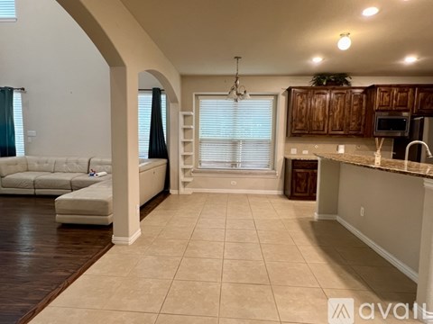 A spacious living room with a white sofa and a kitchen area with brown cabinets.