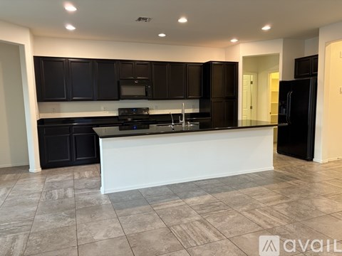 A kitchen with black cabinets and a white island.