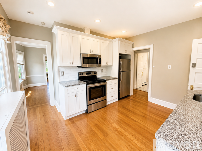 A kitchen with white cabinets and a black stove top oven.