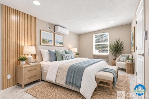 A bedroom with a bed, nightstand, and a plant.