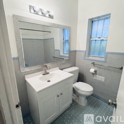 A bathroom with a white sink, toilet, and a mirror above the sink.