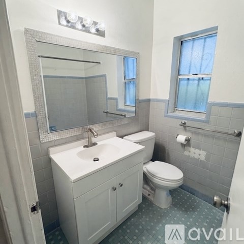 A bathroom with a white sink, toilet, and a mirror above the sink.