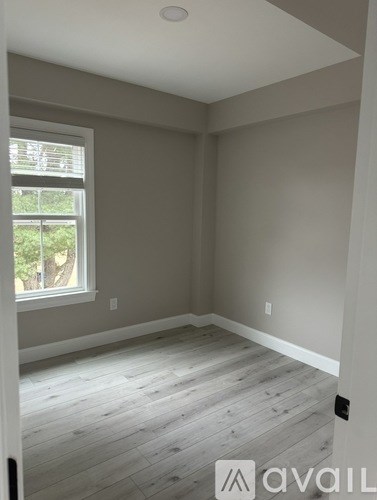 A room with a window and wooden flooring.