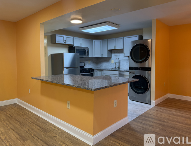 A kitchen with orange walls and a countertop with a dishwasher and microwave.