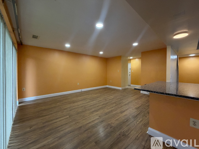 A spacious room with wooden flooring and a counter on the right side.