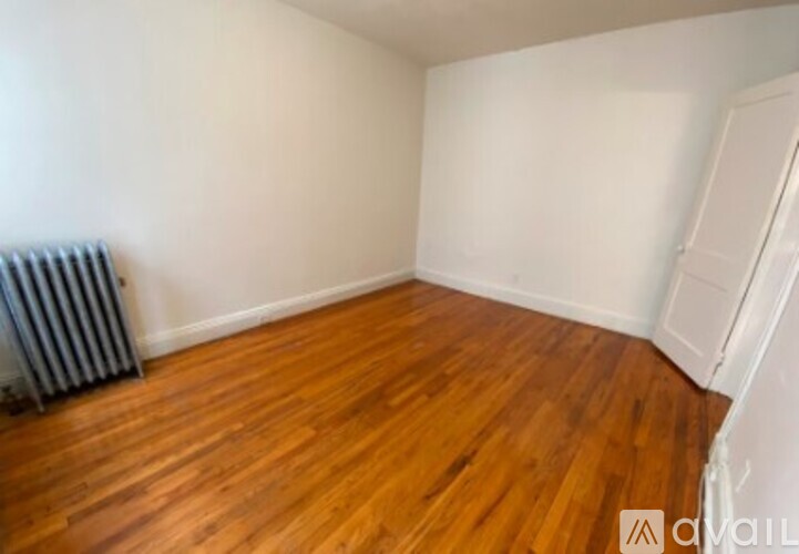 A room with wooden flooring and a white wall.